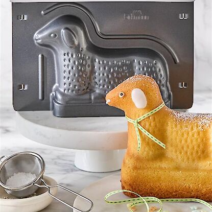 Klassisches Osterlamm aus R&uuml;hrteig, mit Puderzucker best&auml;ubt und auf gr&uuml;ner Platte angerichtet