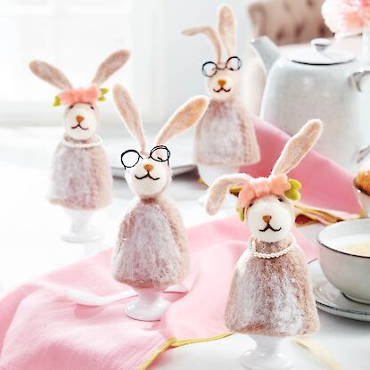 Filzhasen als Osterdekoration auf gedecktem Fr&uuml;hst&uuml;ckstisch mit Kaffee, Croissants und Erdbeeren in hellem Ambiente.