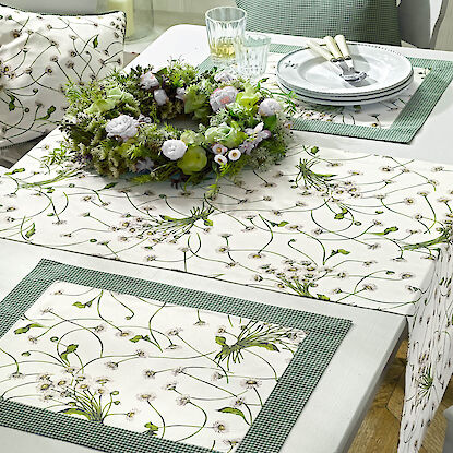 Fr&uuml;hlingshafte Tischw&auml;sche mit Bl&uuml;tenmuster in Gr&uuml;n-Wei&szlig;, gedeckter Tisch mit Kranz, Geschirr und Gl&auml;sern.
