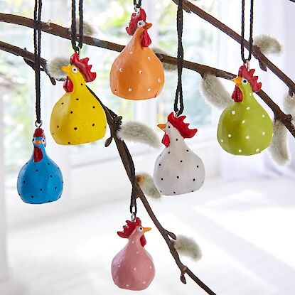 Bunte H&uuml;hner-Anh&auml;nger aus Keramik als Fr&uuml;hlingsdekoration, aufgeh&auml;ngt an Zweigen mit Weidenk&auml;tzchen.