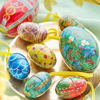 &OElig;ufs de P&acirc;ques richement d&eacute;cor&eacute;s aux motifs floraux et graphiques, dispos&eacute;s sur un plateau dor&eacute; comme d&eacute;coration pascale