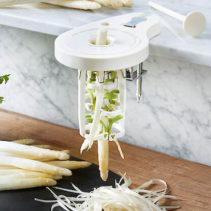 Spargelsch&auml;ler mit Kurbel am Tisch befestigt, sch&auml;lt wei&szlig;en Spargel in feine Streifen