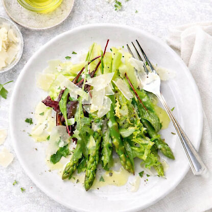Gr&uuml;ner Spargelsalat mit Parmesan, Oliven&ouml;l und Blattsalat auf Teller