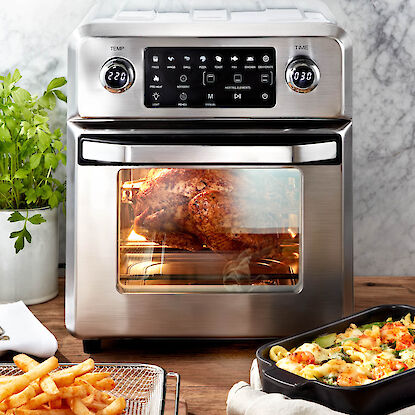 Hei&szlig;luftofen mit Brath&auml;hnchen im Garraum, Pommes und Auflauf auf K&uuml;chenarbeitsplatte