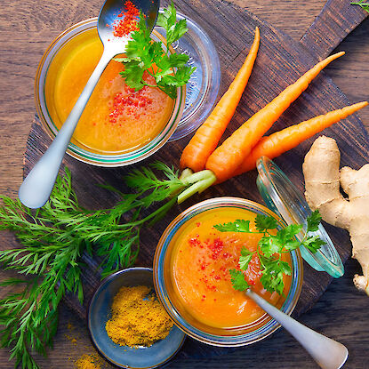 Karottensuppe im Glas mit frischen Karotten, Ingwer, Kr&auml;utern und Gew&uuml;rzen