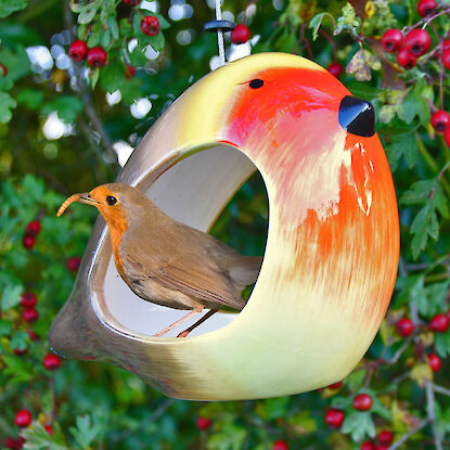 Vogelhaus in Form eines Rotkehlchens mit kleinem Vogel im Garten an Zweig aufgeh&auml;ngt