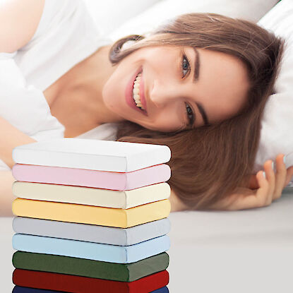 Spannbettlaken in verschiedenen Farben, kombiniert mit einer entspannt liegenden Frau auf einem Bett