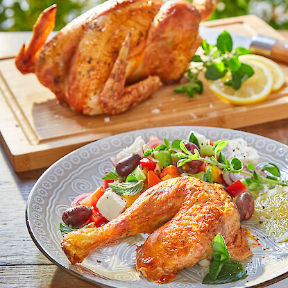 Gegrilltes H&auml;hnchen mit knuspriger Haut, serviert mit mediterranem Salat, Zitrone und Kr&auml;utern auf Teller