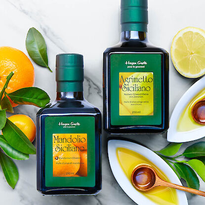 Oliven&ouml;l mit Zitrone und Mandarine aus Sizilien, dekoriert mit Zitrusfr&uuml;chten und Bl&auml;ttern auf hellem Untergrund