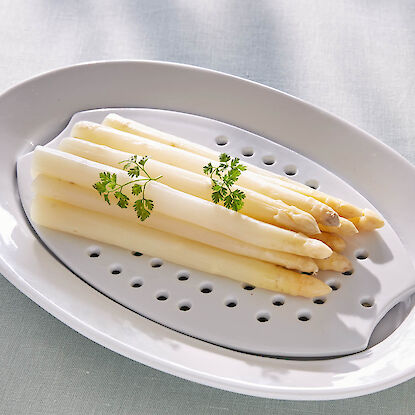 Gekochter wei&szlig;er Spargel auf Servierplatte mit Abtropfeinsatz, garniert mit Petersilie