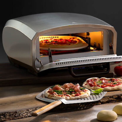 Kompakter Pizzaofen mit frischer Pizza und Pizzaschieber, ideal f&uuml;r knusprige Ergebnisse zu Hause