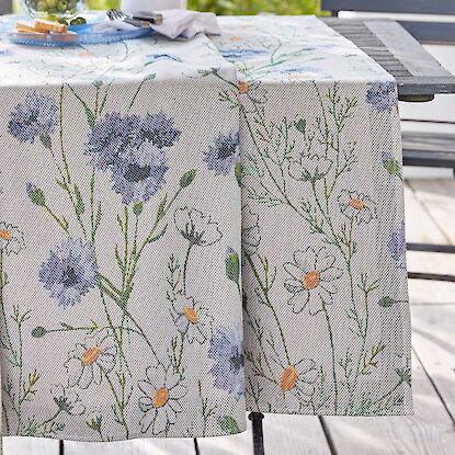Tischdecke mit floralem Wiesenblumenmuster auf gedecktem Gartentisch