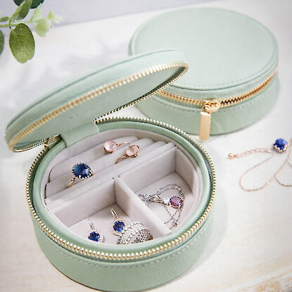 Runde Schmuckbox in Mintgr&uuml;n mit Rei&szlig;verschluss, gef&uuml;llt mit Ringen, Ohrringen und Ketten, dekorativ arrangiert