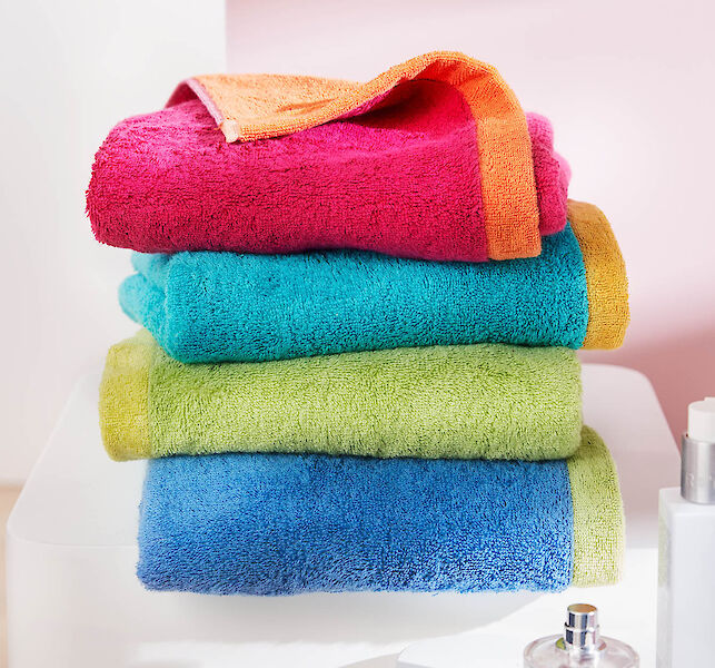 Stapel bunter Handt&uuml;cher in Pink, T&uuml;rkis, Gr&uuml;n und Blau, weich und dekorativ im Badezimmer arrangiert