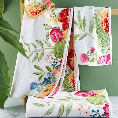 Florale Handt&uuml;cher mit buntem Blumenmuster auf Holzleiter im Badezimmer