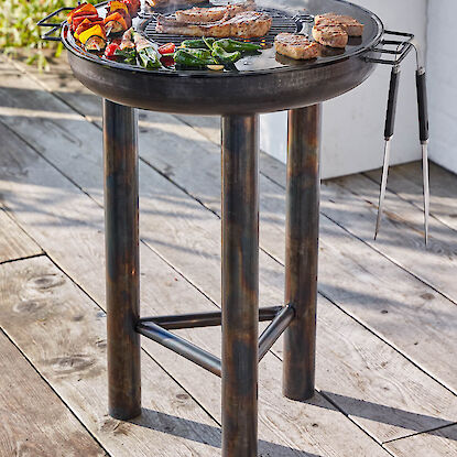Barbecue rond au charbon sur trois pieds avec viande, l&eacute;gumes et brochettes, id&eacute;al pour griller au jardin