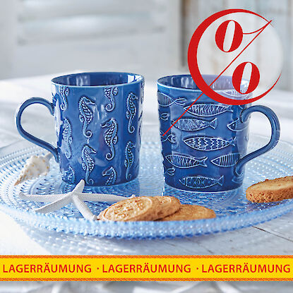 Rabattierte blaue Keramiktassen mit maritimen Motiven auf Glastablett bei Lagerr&auml;umung