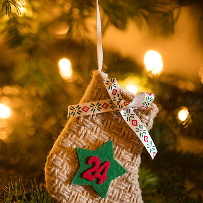 Petit sac tricoté de l'Avent avec le numéro 24, suspendu festivement au sapin de Noël.