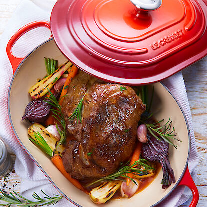 Viande braisée avec des légumes dans une cocotte rouge sur une table.