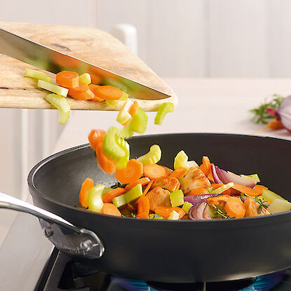 Des légumes sont sautés dans une poêle sur la cuisinière.