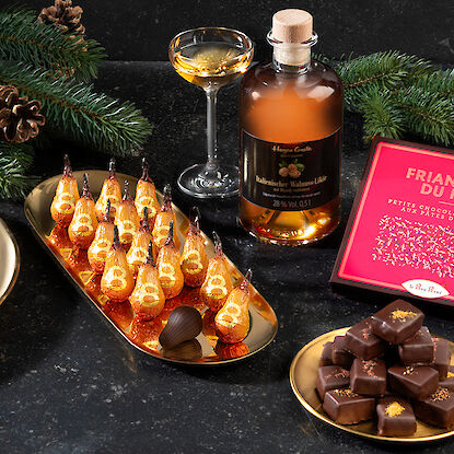 Sélection festive de pralines avec branches de sapin et liqueur de noix.