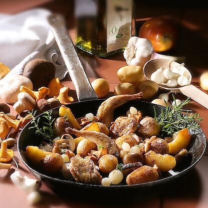 Cailles rôties avec pommes de terre et champignons dans une poêle.