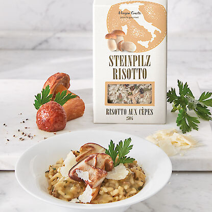 Steinpilz-Risotto in einer Schale, daneben eine Packung Steinpilz-Risotto auf einem Marmortisch.