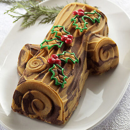 Une bûche de Noël aux motifs de chocolat et vanille, décorée de feuilles de houx vertes et de baies rouges.