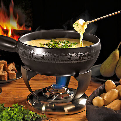 Set à fondue avec fromage fondu, pommes de terre, pain et herbes.