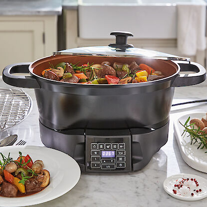 Multicuiseur sur une table de cuisine avec un ragoût de légumes et de viande, à côté d'une assiette servie.