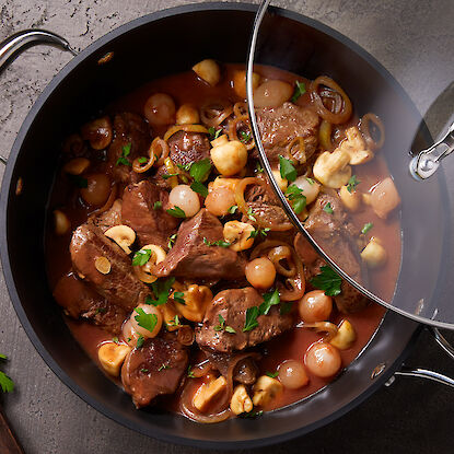 Casserole avec un ragoût de bœuf, garni d'oignons, de champignons et de persil.