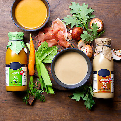 Deux bouteilles de crèmes de soupe avec des légumes, du jambon et des champignons.