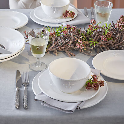 Table dressée de façon festive avec de la vaisselle blanche, des couverts en argent et des verres à vin