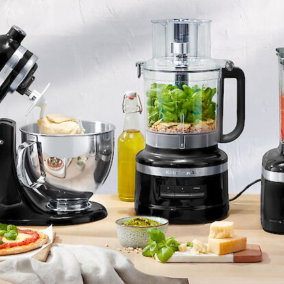 Robots de cuisine KitchenAid avec pizza préparée, pesto et ingrédients frais.