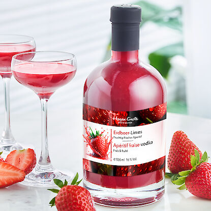 Bouteille d'apéritif à la fraise avec verres de cocktail et fraises fraîches sur une table.