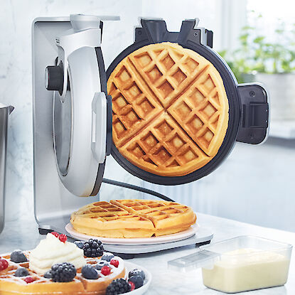 Gaufrier avec gaufre cuite et gaufre garnie de fruits rouges et de crème.