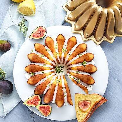 Gâteau au citron et figues fraîches décoré avec du glaçage au sucre, présenté avec un moule doré.