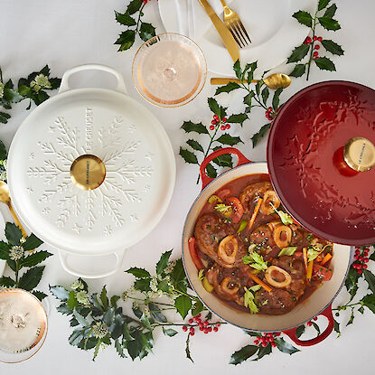 Deux cocottes, l'une ouverte avec un plat de viande, décorées pour Noël.