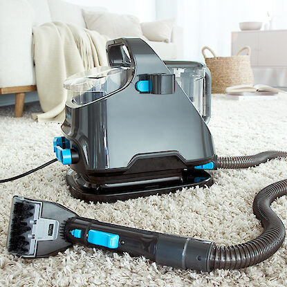 Aspirateur-laveur sur tapis dans un salon.