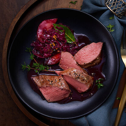 Fleischstücke mit Rotkohl und Apfelscheiben.