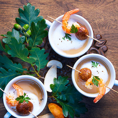 Soupe crémeuse, garnie de crevettes et de champignons sur des brochettes.