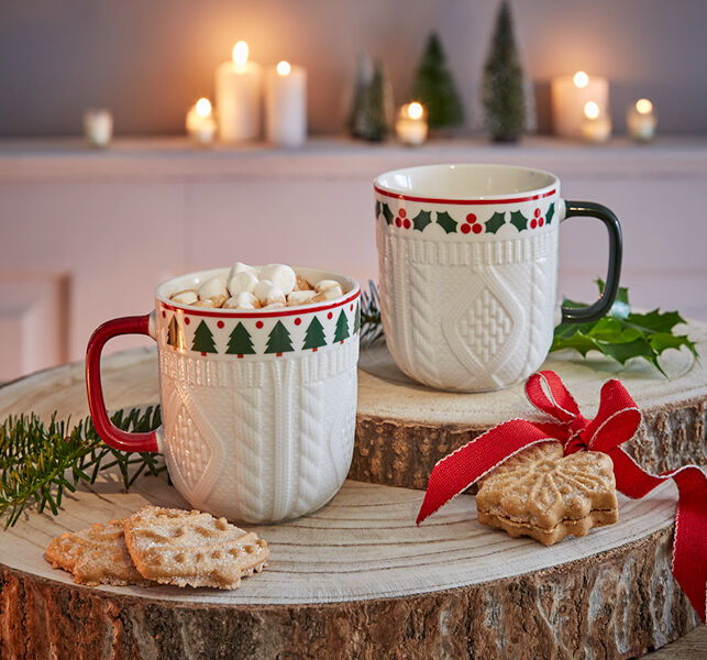 weihnachtlich dekorierte Tassen, eine gefüllt mit heißer Schokolade