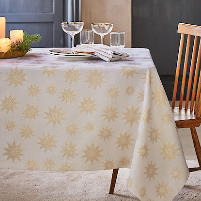 Table dressée de façon festive avec une nappe blanche décorée de étoiles dorées