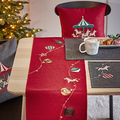 Table décorée avec un chemin de table rouge orné de motifs de chevaux de carrousel et d'ornements