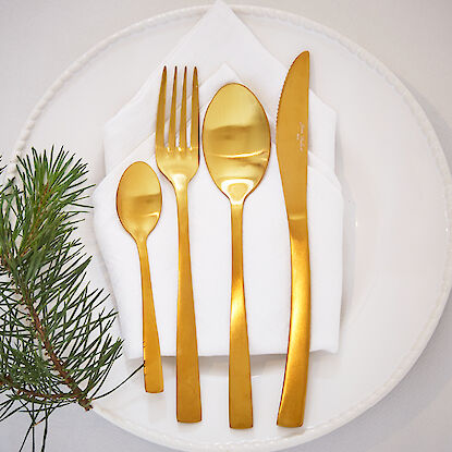 Assiette dressée de façon festive avec des couverts en or, élégamment posée sur une serviette blanche