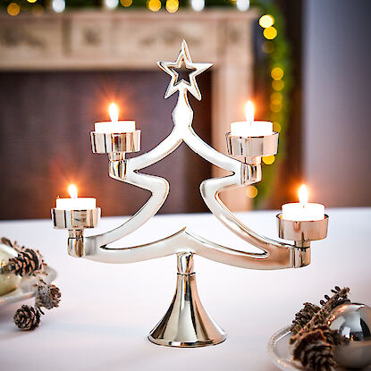 Un chandelier moderne en argent en forme de sapin de Noël avec quatre bougies chauffe-plat allumées