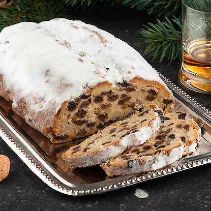 Stollen tranché saupoudré de sucre glace sur un plateau de service en argent.