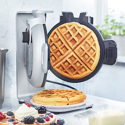 Gaufrier avec une gaufre fraîche et une gaufre garnie de crème chantilly.