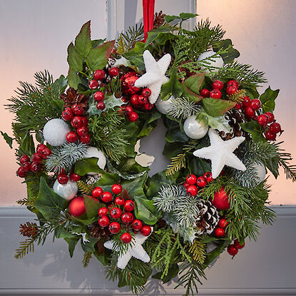 Weihnachtskranz mit roten Beeren, weißen Sternen, Kugeln und Tannenzweigen