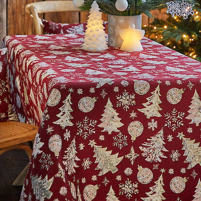 Rot-gemusterte Tischdecke mit Weihnachtsmotiven wie Tannenbäumen, Schneeflocken und Christbaumkugeln